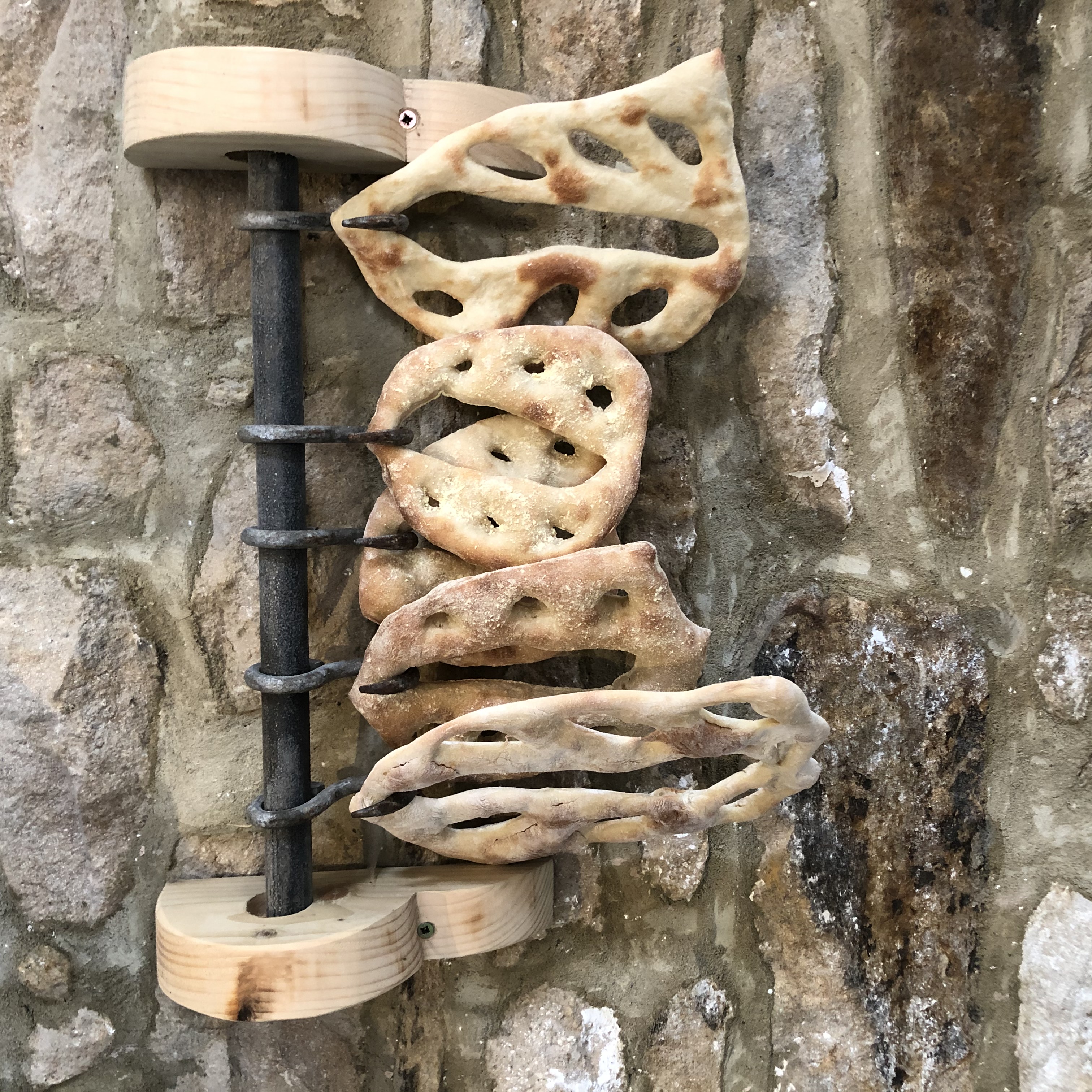 fougasse bread hanging against a stone wall